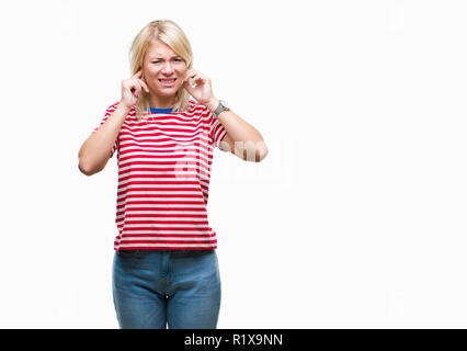 Junge hübsche blonde Frau über isolierte Hintergrund die Ohren mit Fingern mit genervten Ausdruck für den Lärm der laute Musik. Taube Konzept. Stockfoto