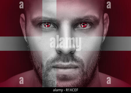 Portrait einer jungen ernster Mann, in dessen Augen die reflektierte Nationalflagge von Dänemark, gegen einen isolierten schwarzen Hintergrund und Flag Stockfoto