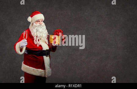 Santa Claus mit einem Geschenk und einem Glas Champagner. Stockfoto