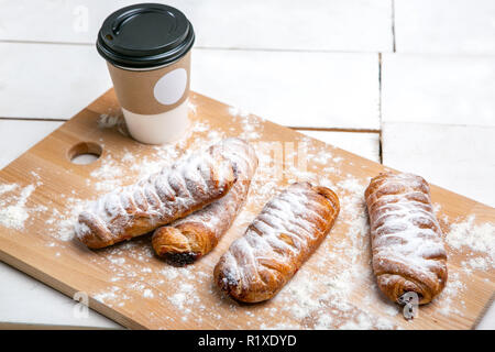 Heiße Tasse Kaffee mit Kuchen auf dem hölzernen Tisch auf weißem Hintergrund. Schnelles Frühstück. Französische Küche. Guten Morgen. Stockfoto