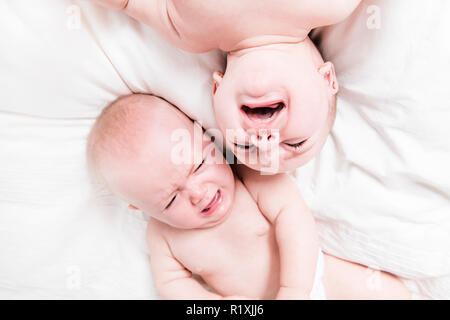 Zwei Babys schreien und liegend auf Bett Stockfoto