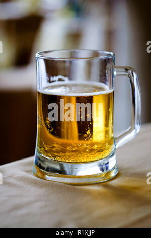 Eine riesige Glastasse frischen Bier im Restaurant auf der weißen Tischdecke. Stockfoto