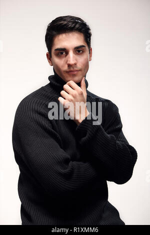 Ein junger stattlicher Mann, stattliches Modell, 20-29 Jahre alt, posiert im Studio, Foto schießen. Weiß isoliert Hintergrund. legere Kleidung. mit schwarzen Schweiß Stockfoto