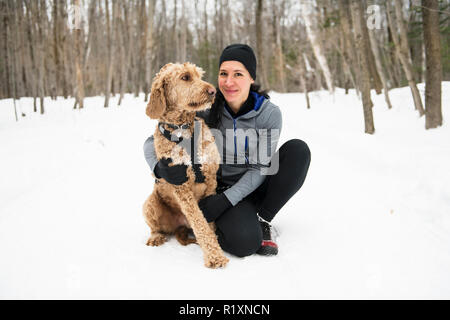 Eine Frau mit goldendoodle Wintersaison Stockfoto