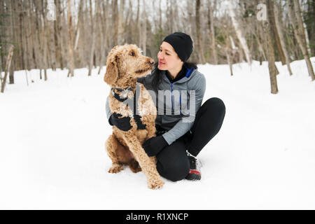 Eine Frau mit goldendoodle Wintersaison Stockfoto