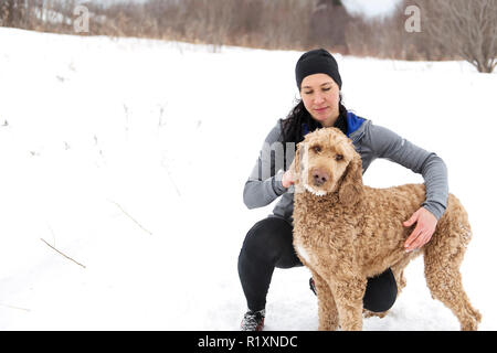 Eine Frau mit goldendoodle Wintersaison Stockfoto