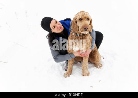 Eine Frau mit goldendoodle Wintersaison Stockfoto