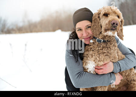 Eine Frau mit goldendoodle Wintersaison Stockfoto