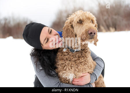 Eine Frau mit goldendoodle Wintersaison Stockfoto