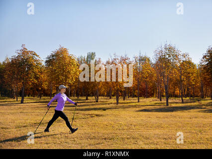 Junge aktive Frau tun Nordic walking Übung im Herbst Park Stockfoto