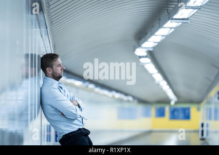 Der jungen Arbeitslosen business Mann leiden Depressionen lehnte sich auf Street U-Wand allein suchen verzweifelt in emotionalen Schmerz psychische Gesundheit Unemploymen Stockfoto
