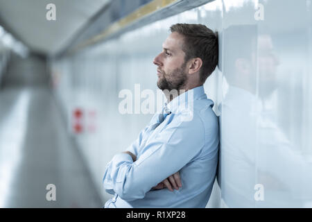 Der jungen Arbeitslosen business Mann leiden Depressionen lehnte sich auf Street U-Wand allein suchen verzweifelt in emotionalen Schmerz psychische Gesundheit Unemploymen Stockfoto
