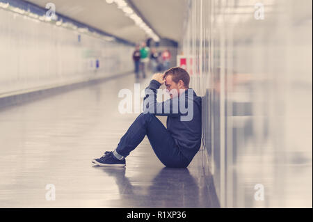 Miserable arbeitslose junge Mann weinen Drogensüchtigen Obdachlosen in Depression stress sitzen auf dem Boden Street U-Bahn Tunnel suchen verzweifelt lehnte sich an der Wand Stockfoto