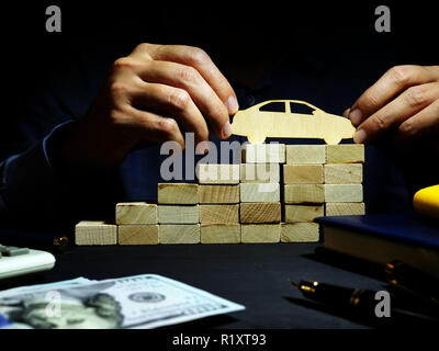 Einsparungen für den Kauf von Autos. Treppen aus Holz Blöcke und Modell des Autos. Stockfoto