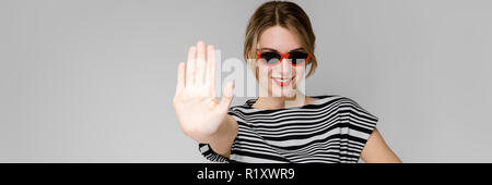 Junges Mädchen mit Brille zeigt ein Handzeichen anhalten. Stockfoto