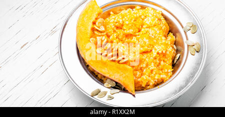 Hausgemachte leckere Porridge mit orange Kürbis auf weißem Hintergrund. Gesundes Frühstück. Stockfoto