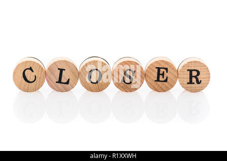 Wort aus kreisförmigen Holz Fliesen näher mit Buchstaben Kinder Spielzeug. Konzept der Nähe in Kinderspielzeug Buchstaben geschrieben. Stockfoto