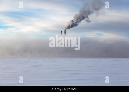 Rauch Rohre in dichtem Nebel im Winter auf einem Hintergrund bewölkter Himmel Stockfoto