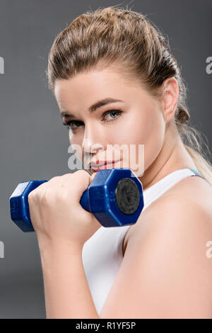 Nahaufnahme der jungen Frau Training mit Hanteln und Kamera isoliert auf Grau Stockfoto