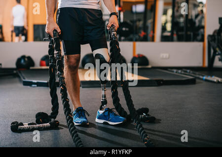 7/8 Schuß von Sportler mit künstlichen Bein arbeiten mit Seilen im Fitnessstudio Stockfoto