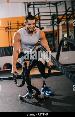 Hübscher junger Sportler mit künstlichen Bein arbeiten mit Seilen im Fitnessstudio Stockfoto