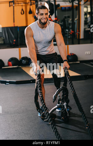 Muskulöse junge Sportler mit künstlichen Bein arbeiten mit Seilen im Fitnessstudio Stockfoto