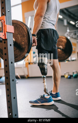 7/8 Schuß von fit Sportler mit künstlichen Bein arbeiten mit Langhantel im Fitnessstudio Stockfoto