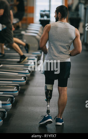 Ansicht der Rückseite des Kraftsportlers mit künstlichen Bein zu Fuß durch Fitnessraum Stockfoto