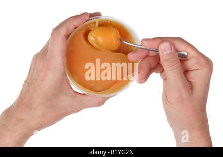 Ein älterer Mann nimmt Biene goldene Farbe Honig aus einem Kunststoff Schale mit einem Löffel. Auf weissem Studio closeup Schuß isoliert Stockfoto