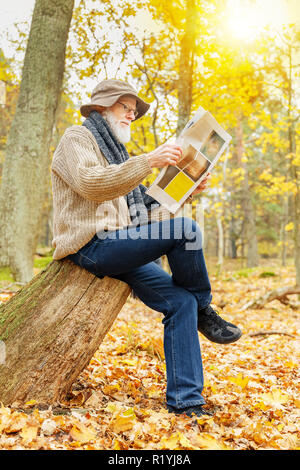 Älterer mann lesen Zeitung draußen im Wald im Herbst Stockfoto