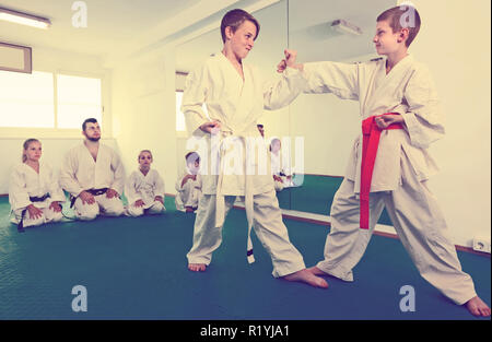 Freundlich froh jungen Ausbildung in paar Karate Technik während der Klasse zu verwenden Stockfoto