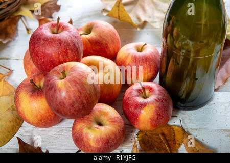 Blätter im Herbst mit einer Flasche Apfelwein und und Äpfel Stockfoto