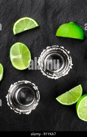 Zwei tequila Schüsse mit Kalk Schichten und Keile, Schuß von oben auf schwarzem Hintergrund Stockfoto