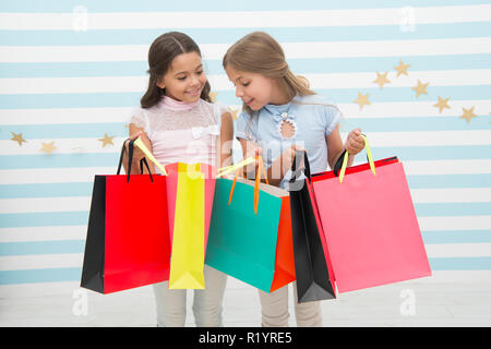 Einkaufen mit beste Freundin Konzept. Mädchen wie einkaufen. Die Kinder glücklich kleine Mädchen halten Einkaufstaschen. Viel Spaß beim Shoppen mit der besten Freundin oder Schwester. Mädchenhafte Glück. Die Kinder glücklich tragen Bündel Pakete. Stockfoto