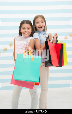 Mädchen wie einkaufen. Die Kinder glücklich kleine Mädchen halten Einkaufstaschen. Viel Spaß beim Shoppen mit der besten Freundin oder Schwester. Mädchenhafte Glück. Die Kinder glücklich tragen Bündel Pakete. Einkaufen mit beste Freundin Konzept. Stockfoto