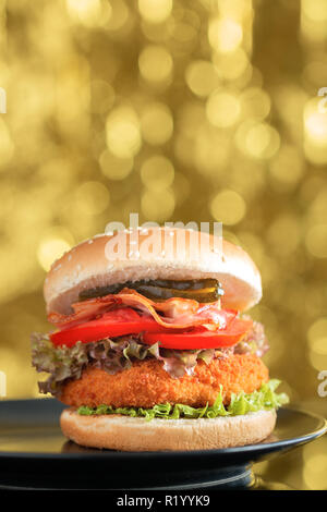 Eine gesunde, hausgemachten Burger mit Zwiebeln, Salat und Tomaten auf einem goldenem Hintergrund. Stockfoto