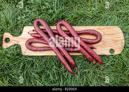 Slowakischen Würstchen aus Schweinefleisch auf einem Holzbrett auf Gras, Serbien Stockfoto