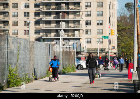 NEW YORK - USA - 31. Oktober 2017. Eine Frau ist zu Fuß durch die Straßen von Harlem mit einer Einkaufstasche in der Hand. New York City, USA. Stockfoto