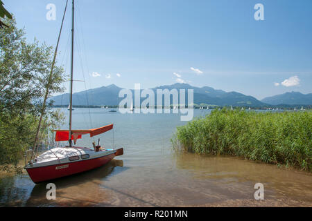 Chiemsee. Segelboot an der Küste mit Insel Herreninsel im Hintergrund, Bayern, Deutschland Stockfoto