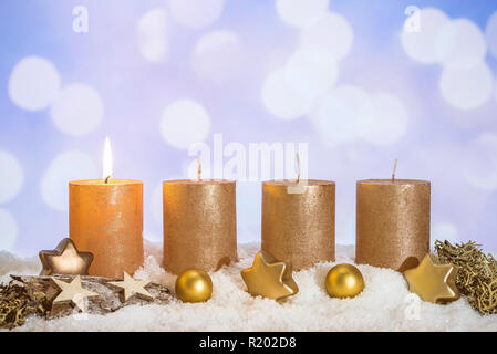 Vier goldene advent Kerzen mit der ersten Kerze angezündet und Weihnachten Dekoration im Schnee liegend als Vorlage Stockfoto