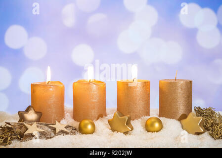 Vier goldene advent Kerzen mit drei Kerzen und Weihnachten Dekoration im Schnee liegend als Vorlage Stockfoto