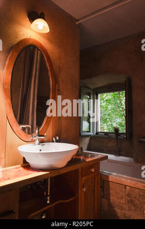 Alte vintage Badezimmer mit modernen Waschbecken und Badewanne mit offenem Fenster und Baum, in der Natur. Stockfoto
