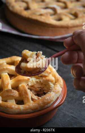 Frau Hand einen Löffel mit einem Stück Apfelkuchen. Süßigkeiten essen. Traditionelle Feiertage pie. Relishing süße Leckereien. Stockfoto