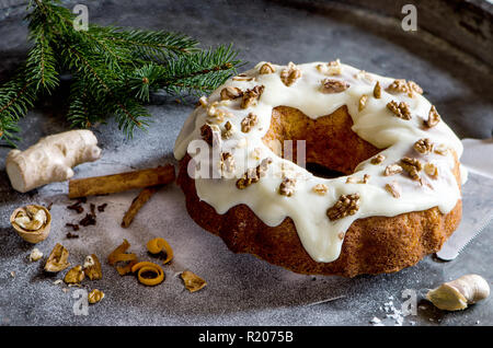 Karotten Ingwer Weihnachten Kuchen auf dem dunklen Hintergrund, dekoriert mit Zimtstangen, Walnüsse, Ingwer, Kiefer brunch und weißer Zucker Stockfoto