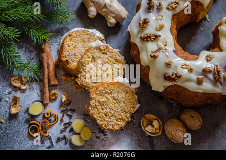 Karotten Ingwer Weihnachten Kuchen auf dem dunklen Hintergrund, dekoriert mit Zimtstangen, Walnüsse, Ingwer, Kiefer brunch und weißer Zucker Stockfoto