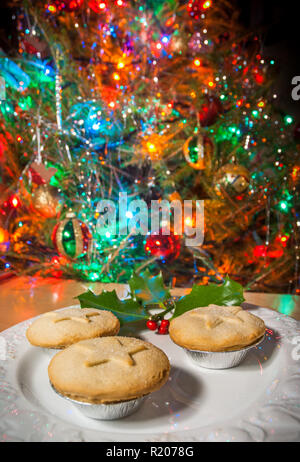 Einen Teller mit Kuchen unter einem Chrsitmas baum Blatt vor den Mund. Stockfoto