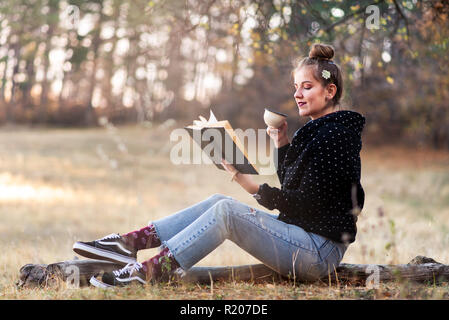 Mädchen ein Buch lesen und eine Tasse Kaffee im Freien Stockfoto