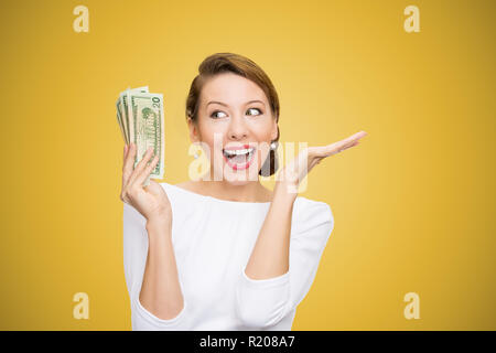 Junge Frau mit Haufen von Dollar aufgeregt Suchen super auf gelben Hintergrund glücklich Stockfoto