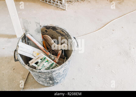 Alte Werkzeuge für den Bau in Farbe sitzen auf staubigen Boden abgedeckt. Eimer, Kübel, Schaufeln, Löffel, Zement, Lineal und Müll Stockfoto