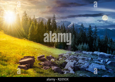 Alpine Landschaft im Sommer Tag und Nacht Zeit ändern Composite. Felsformation in der Nähe des Waldes auf einem grasbewachsenen Hügel Fichte. Berg mit Schnee oben in der d Stockfoto